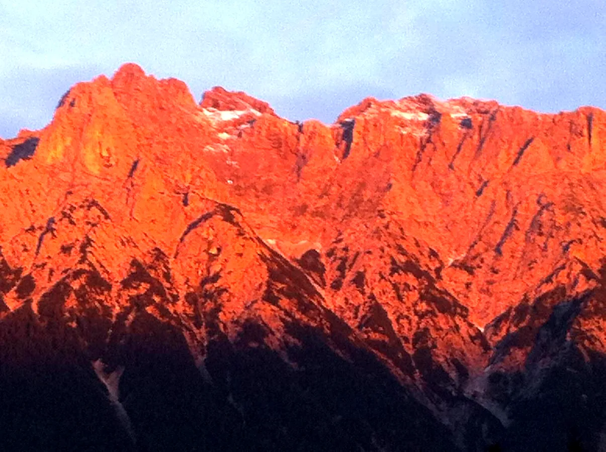 Die Felswand des Karwendels leuchtet orange im letzten Abendlicht, Foto der Bäckeralm
