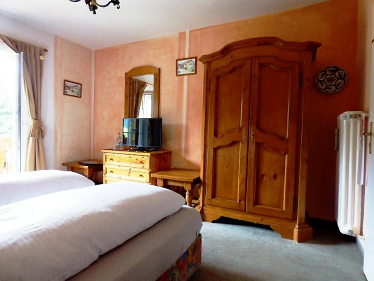 Helles Doppelzimmer mit Bauernschrank aus Holz und Balkontür