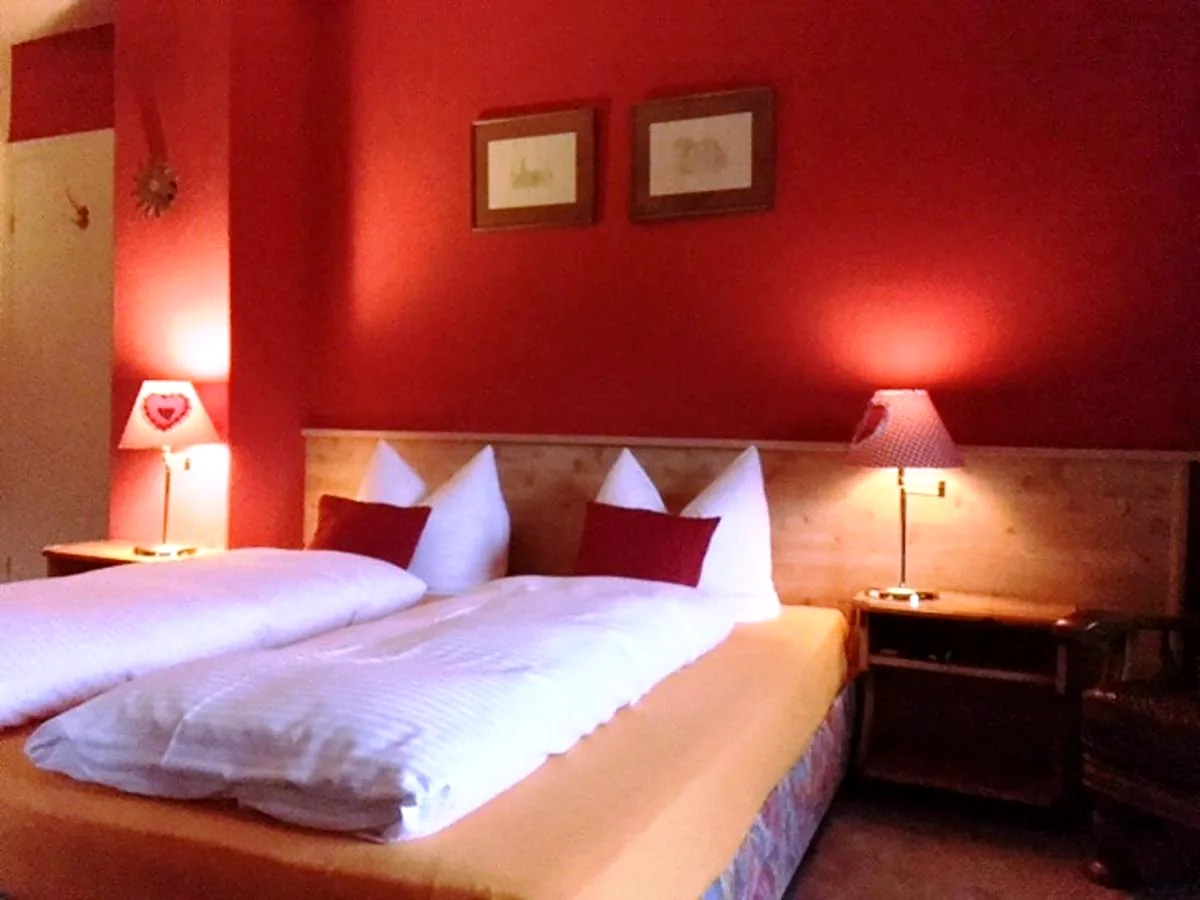 Doppelzimmer mit roten Kissen und Nachttischlampen